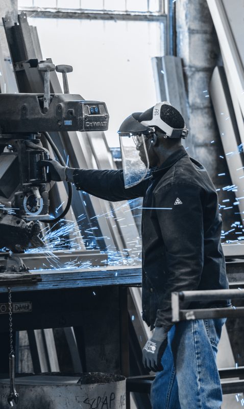 An industrial setting with heavy machinery and a worker equipped with safety gear, controlling the process.