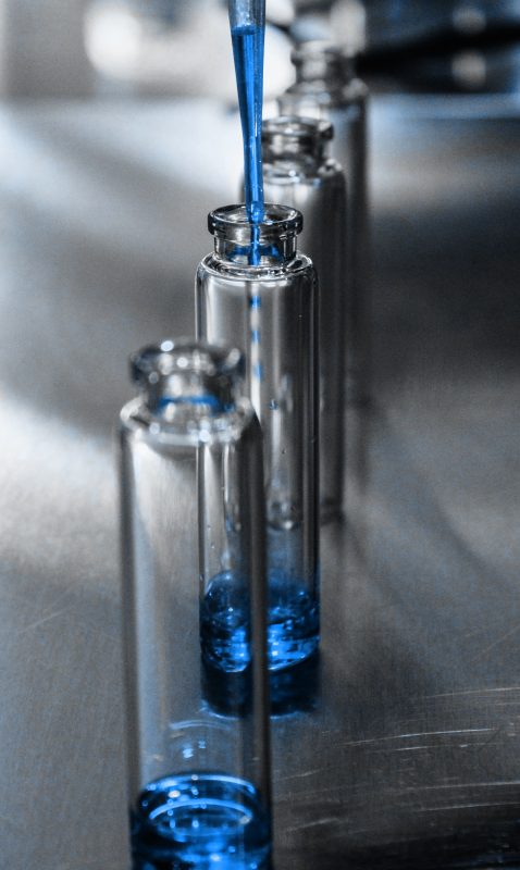 A line-up of glass chemical flask passing the quality control measures in chemical manufacturing setting.