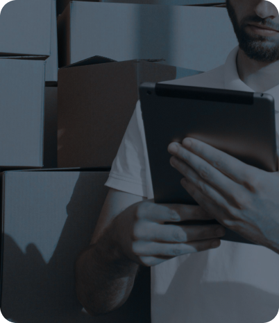 A man holding a tablet in the middle of a warehouse full of goods, demonstrating the fusion of modern technology and basic operations in retail.